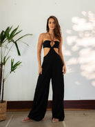 Mulher usando macacão preto da Greenish, com design moderno e recortes, perfeito para o verão.