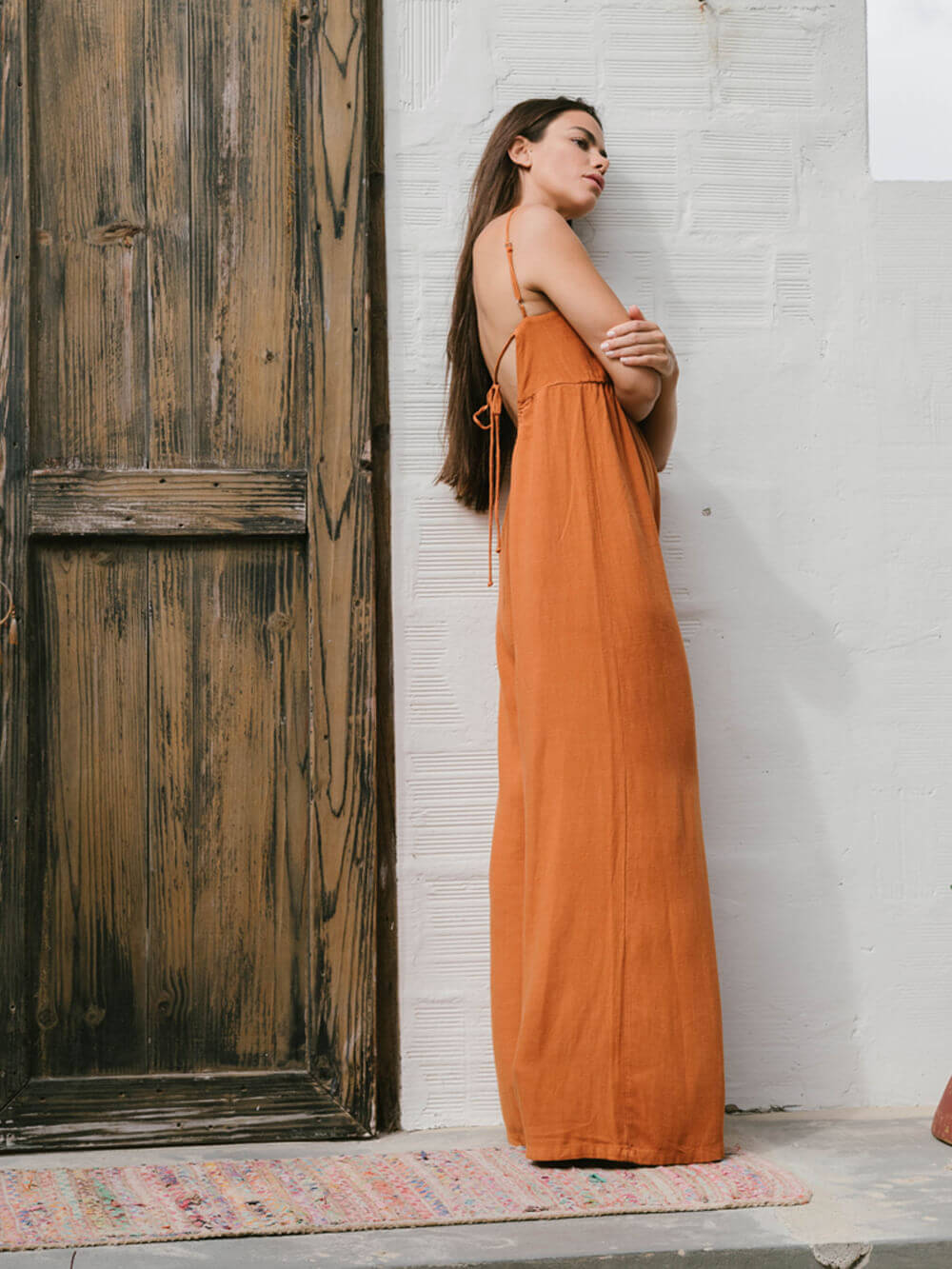 Modelo usando o macacão Mabel laranja da Greenish, com caimento solto e decote quadrado, elegante e confortável.