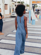 Mulher de vestido midi azul Yala da Greenish, caminhando em uma rua, com cabelo cacheado e detalhe nas costas.