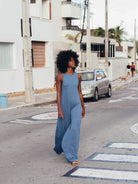 Mulher usando macacão midi Yala azul da marca Greenish, caminhando na rua, estilo moderno e confortável.