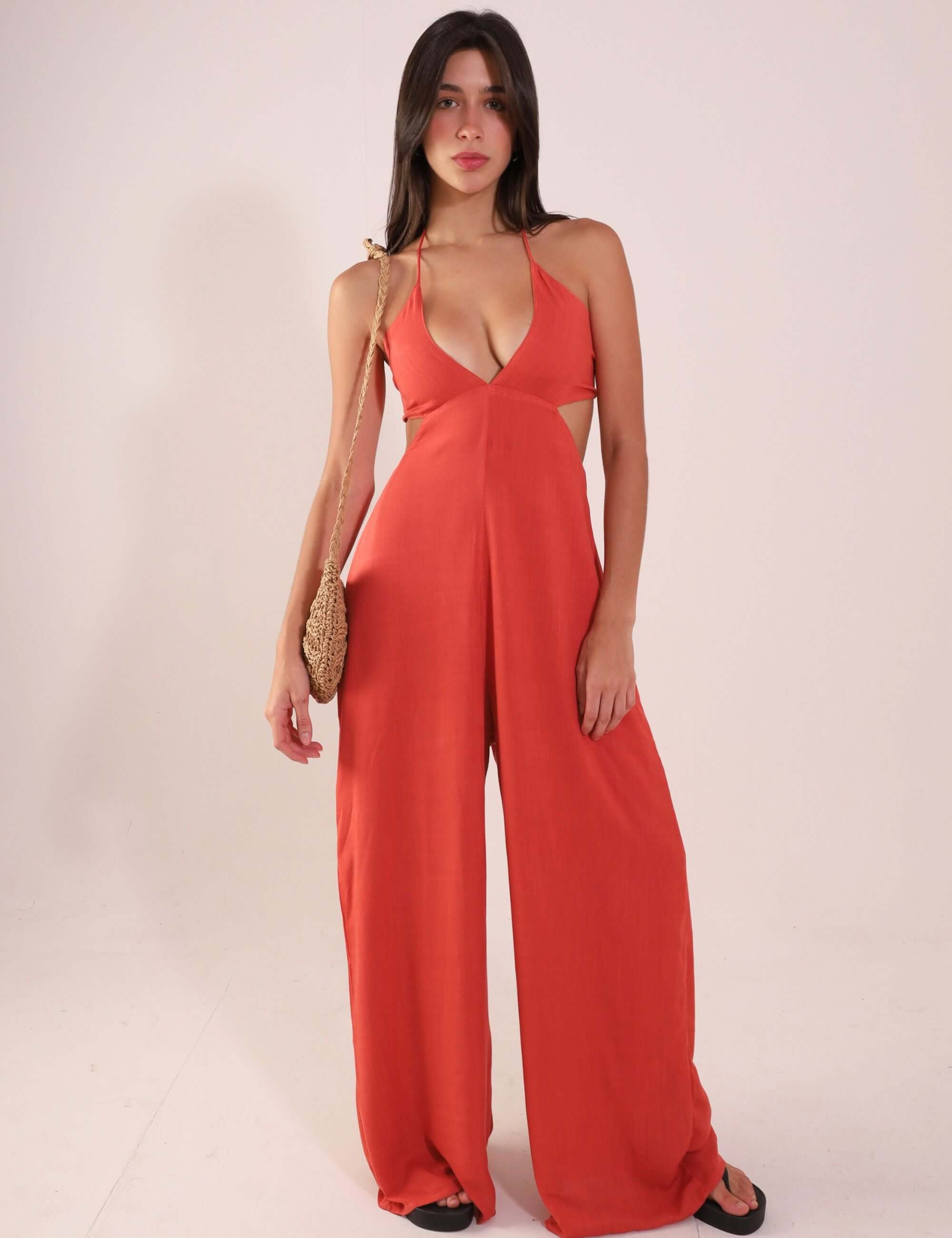 Woman wearing Macacão Rustic - Telha, a stylish and breathable rust-colored jumpsuit with V-neck and adjustable back ties.