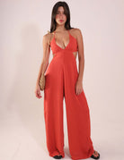 Woman wearing Macacão Rustic - Telha, a stylish and breathable rust-colored jumpsuit with V-neck and adjustable back ties.