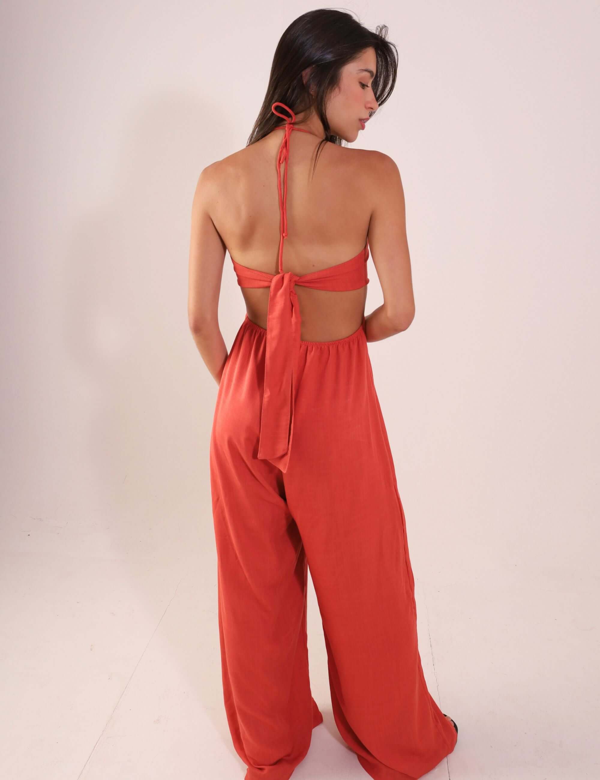 Mulher vestindo Macacão Rustic - Telha, de costas, com alças amarradas e tecido fluido, destacando o ajuste e conforto para dias quentes.