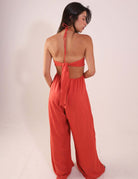 Mulher vestindo Macacão Rustic - Telha, de costas, com alças amarradas e tecido fluido, destacando o ajuste e conforto para dias quentes.