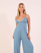 Model wearing Macacão canelado Mariela - Azul Indigo, featuring V-neck and adjustable straps for a perfect fit.