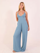 Modelo vestindo Macacão canelado Mariela - Azul Indigo, com decote V e alças amarráveis, destacando a leveza e ajuste perfeito.