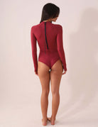 Mulher usando MAIÔ GREENISH BAYSHORE - BORDÔ com mangas longas e zíper nas costas, destacando conforto e proteção solar.