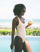 Mulher usando Maiô Gioh - Off White da marca Greenish, desfrutando do dia ensolarado à beira da piscina.