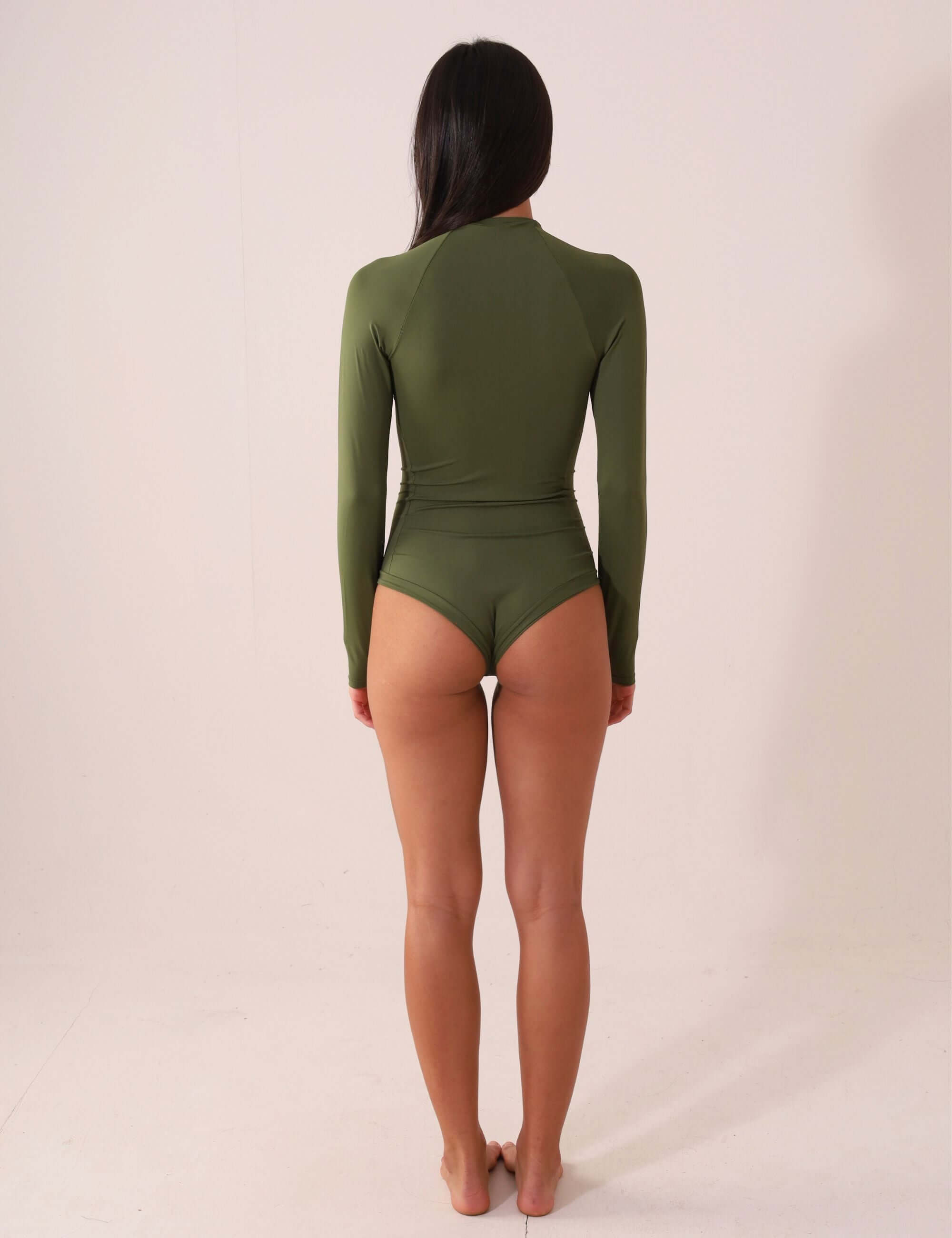 Mulher usando MAIÔ MANGA LONGA ARY - VERDE FLORESTA, costas, por Greenish, com proteção UV, ideal para surf e kite.