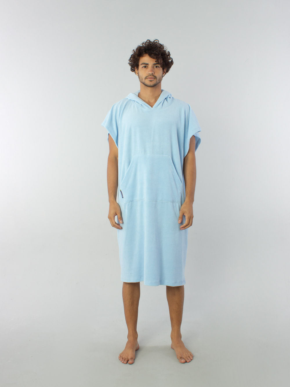 Modelo usando Poncho Adulto Bolso Canguru Azul Claro da Greenish, ideal para conforto na praia e proteção contra o frio.