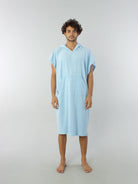 Modelo usando Poncho Adulto Bolso Canguru Azul Claro da Greenish, ideal para conforto na praia e proteção contra o frio.