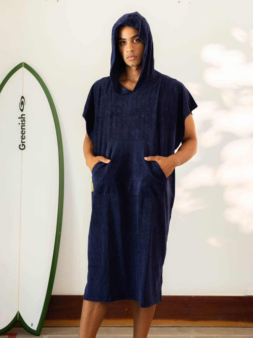 Modelo usando o Poncho Adulto Canguru Azul Marinho da Greenish, com capuz e bolsos, ideal para a praia.