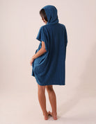 Mulher vestindo PONCHO CURTO CANELADO - AZUL Greenish com touca e bolsos canguru, feito em tecido atoalhado super absorvente e de secagem rápida.