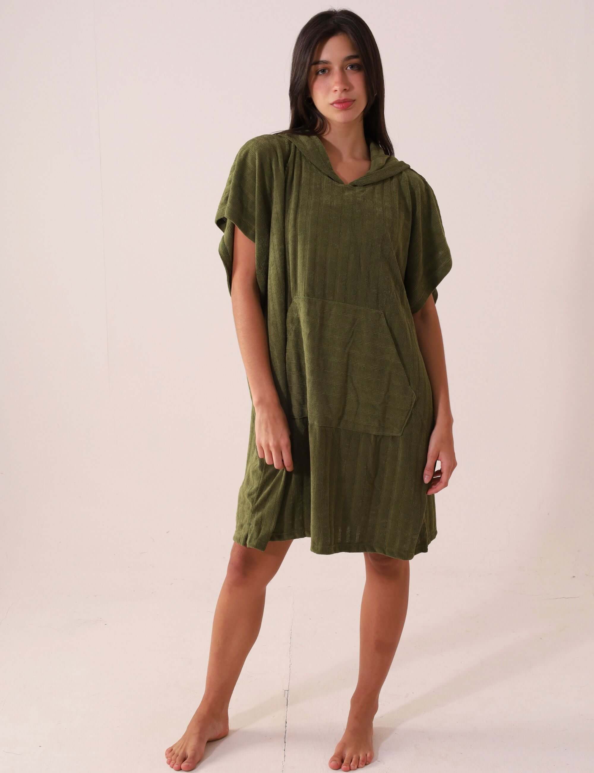 Modelo vestindo PONCHO CURTO CANELADO - VERDE Greenish, ideal para praia com tecido atoalhado e bolsos frontais.