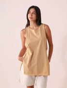 Regata Déa - Caqui da Greenish com design alongado e fendas laterais, ideal para looks casuais e de praia. Modelo vestindo regata em caqui.