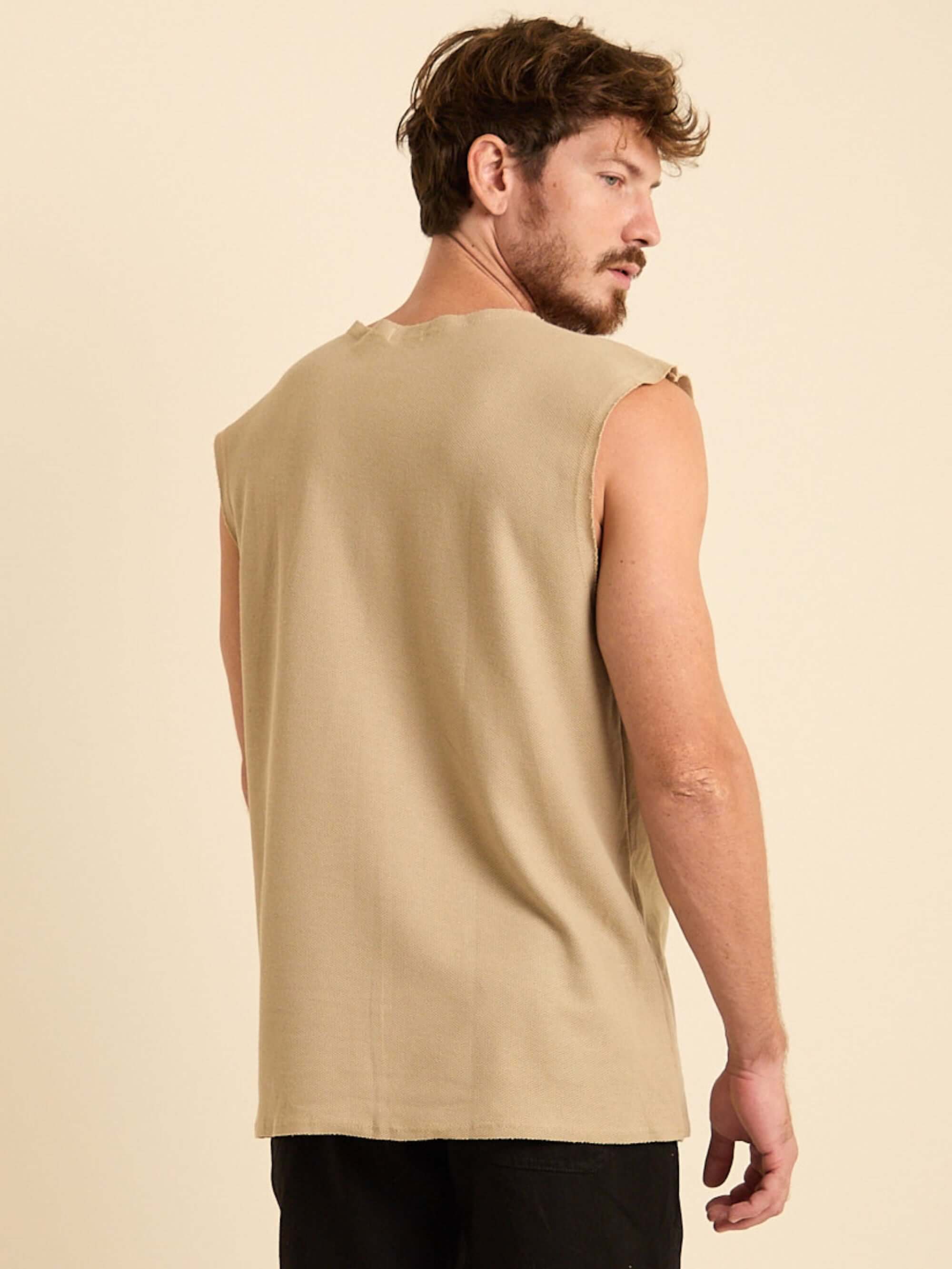 Modelo masculino usando a Regata Larga Maré bege da Greenish, mostrando a parte de trás da peça.