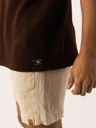 Homem usando regata longa marrom e shorts clarinhos, estilo descontraído e confortável da marca Greenish.