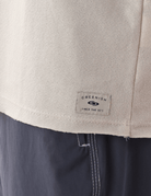 Detalhe da Regata Larga Waves Bege da marca Greenish, mostrando etiqueta discreta e acabamento em tecido texturizado.