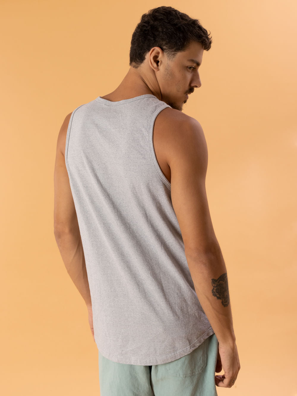 Modelo usando a Regata Listra Stripe em cinza da marca Greenish, destacando o conforto e estilo do produto.