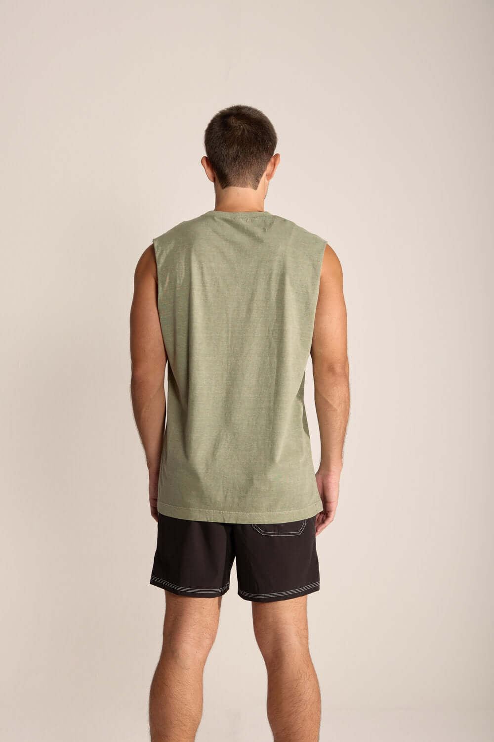 Modelo usando a Regata Masculina Larga Tropical Therapy da Greenish, na cor verde, com estilo relax e confortável.