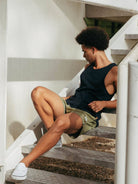 Modelo usando regata ribbed azul marinho da Greenish, sentado em escadas, estilo minimalista e confortável.