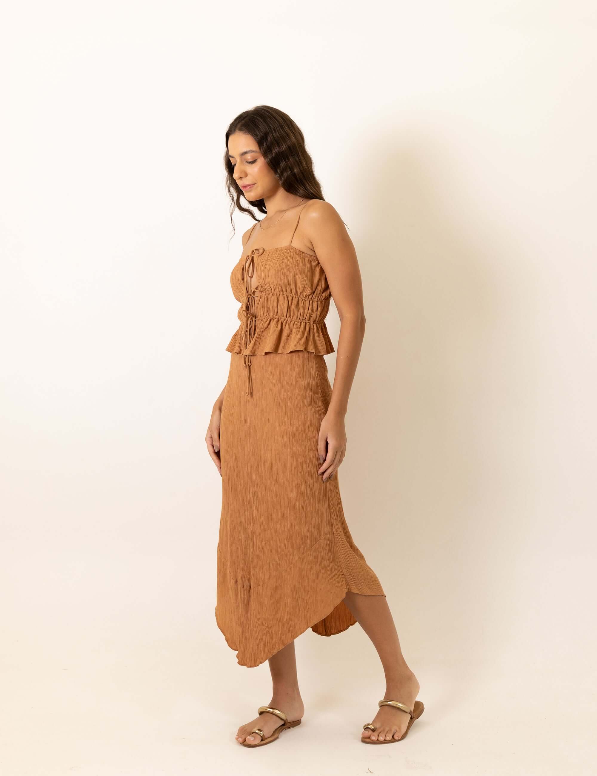 Modelo vestindo Saia Midi Lille - Bege da marca Greenish, feita de viscose enrugada com design assimétrico e detalhe frontal elegante.