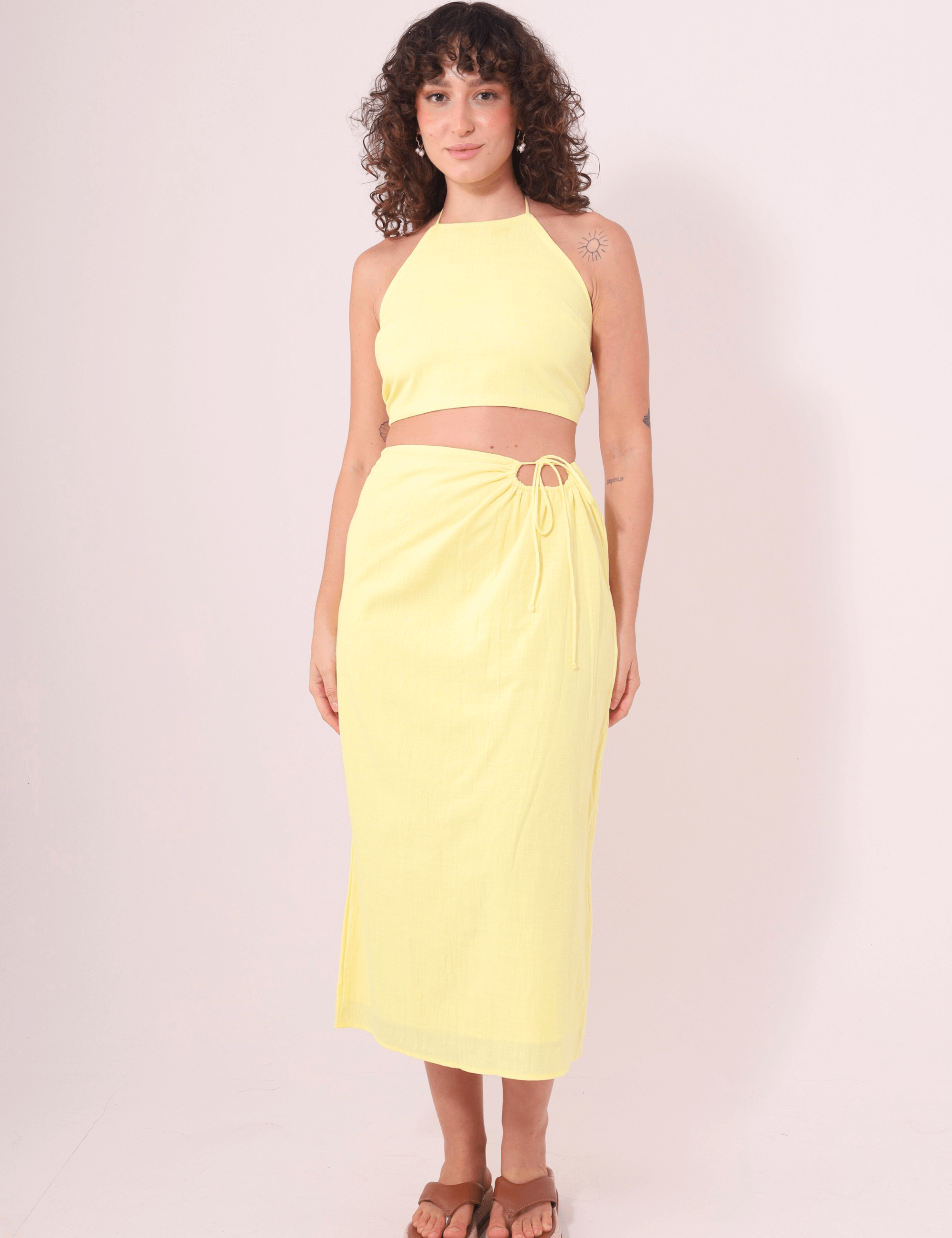 Modelo vestindo Saia Midi Sunny amarela da Greenish, feita em algodão 100%, ideal para dias ensolarados e confortáveis.