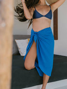 Mulher usando sarong praia Lana azul da marca Greenish, com um estilo descontraído e moderno.