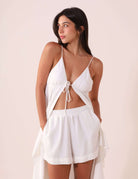 Modelo vestindo SHORT ÁUREA - OFF WHITE da marca Greenish, com design fluido, bolsos laterais e bainha de 4cm. Ideal para dias quentes.