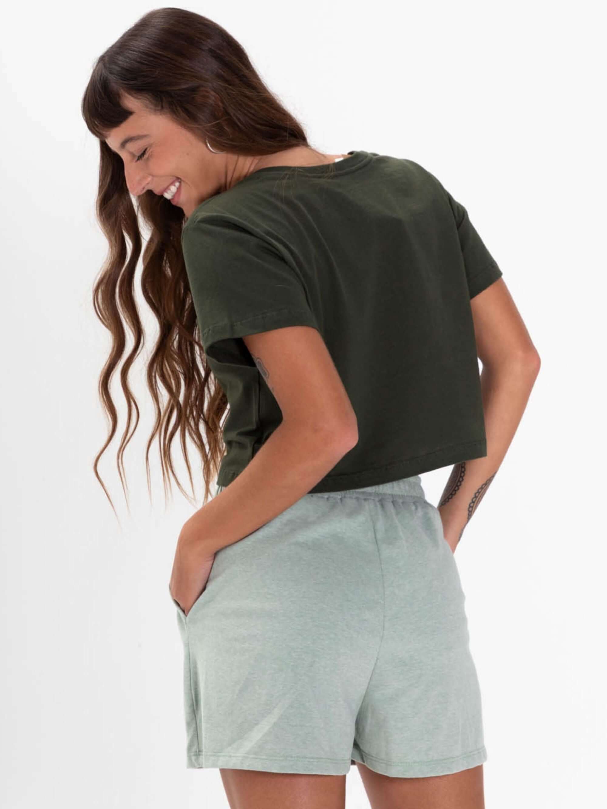 Mulher sorrindo usando o short confortavel Piper Verde da marca Greenish, vista de costas.
