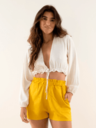 Short Elisa amarelo da marca Greenish, modelo feminino com blusa branca, look casual e moderno.
