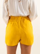 Shorts amarelos da marca Greenish, modelo Elisa, com detalhes na cintura e bolso traseiro.