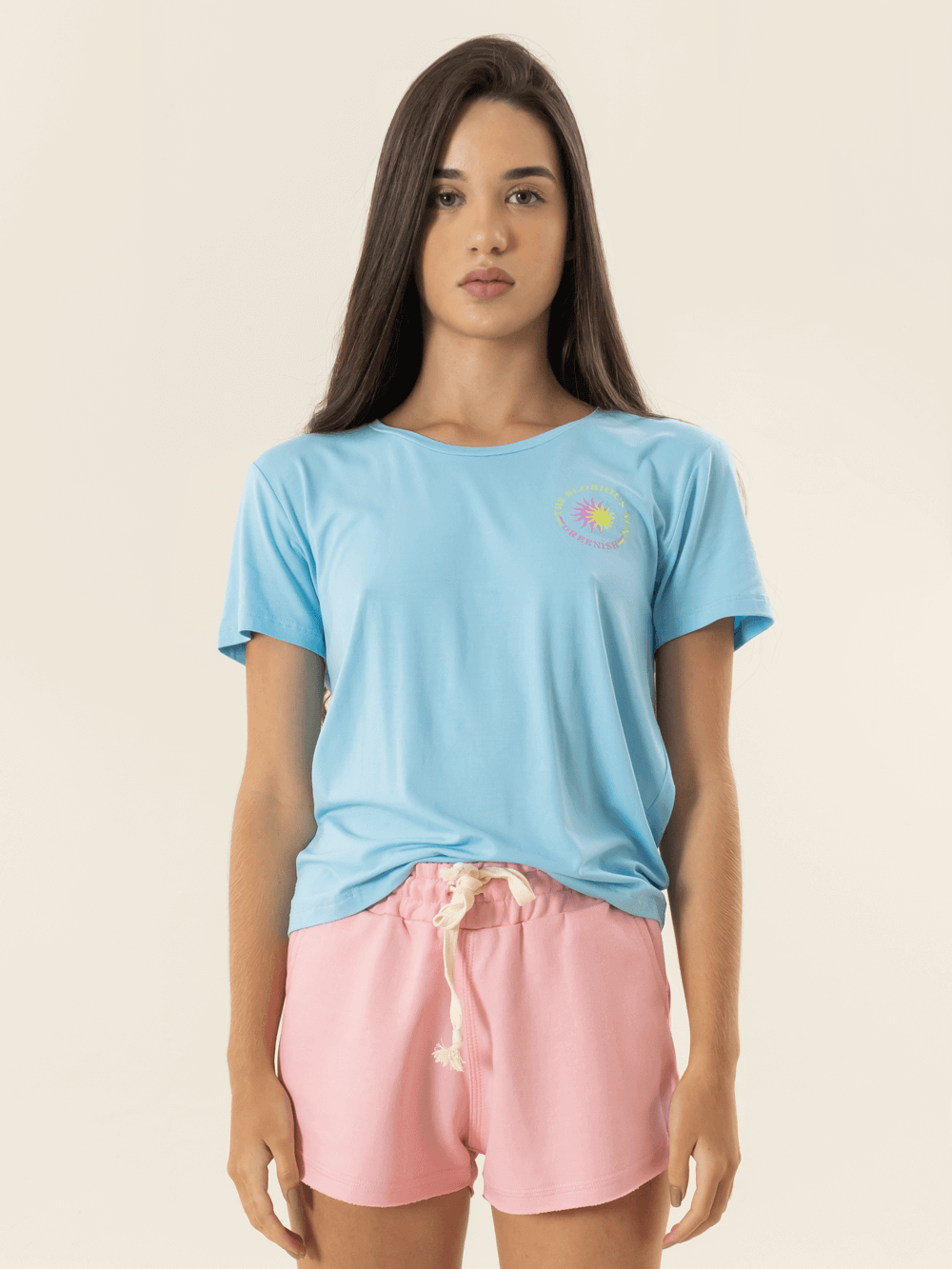  Mulher usando short rosa e camiseta azul da marca Greenish, look moderno e confortável.