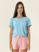  Mulher usando short rosa e camiseta azul da marca Greenish, look moderno e confortável.
