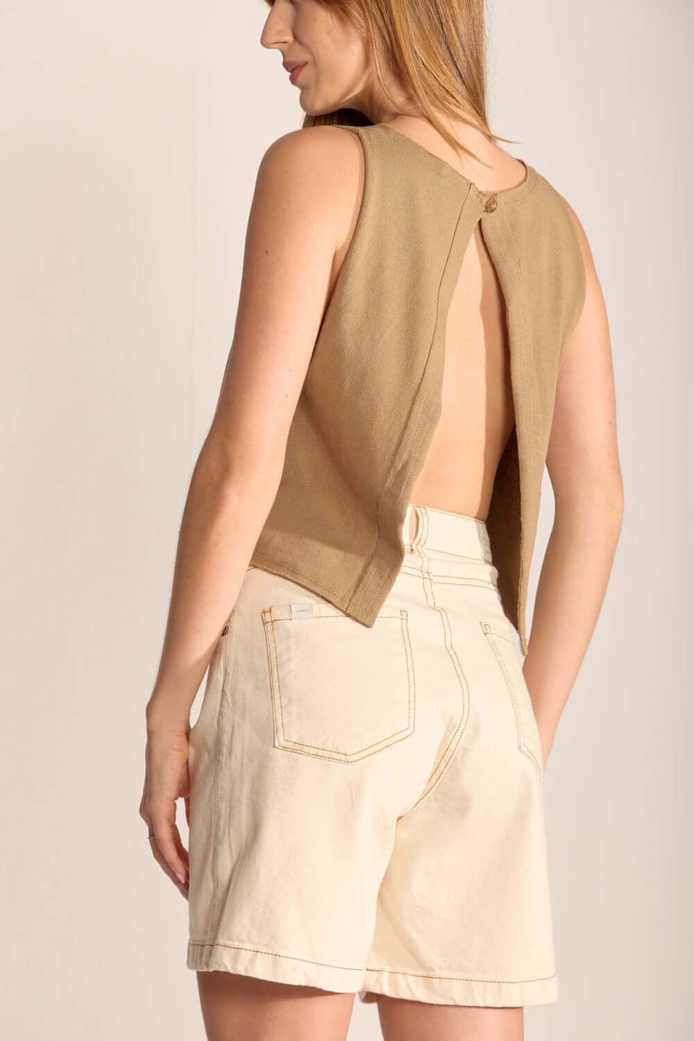 Mulher usando camisa com costas abertas e short curto, look casual e elegante da marca Greenish.