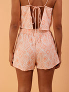 Modelo usando o short LAYA na cor coral, da marca Greenish, com estampa geométrica e detalhe nas costas.