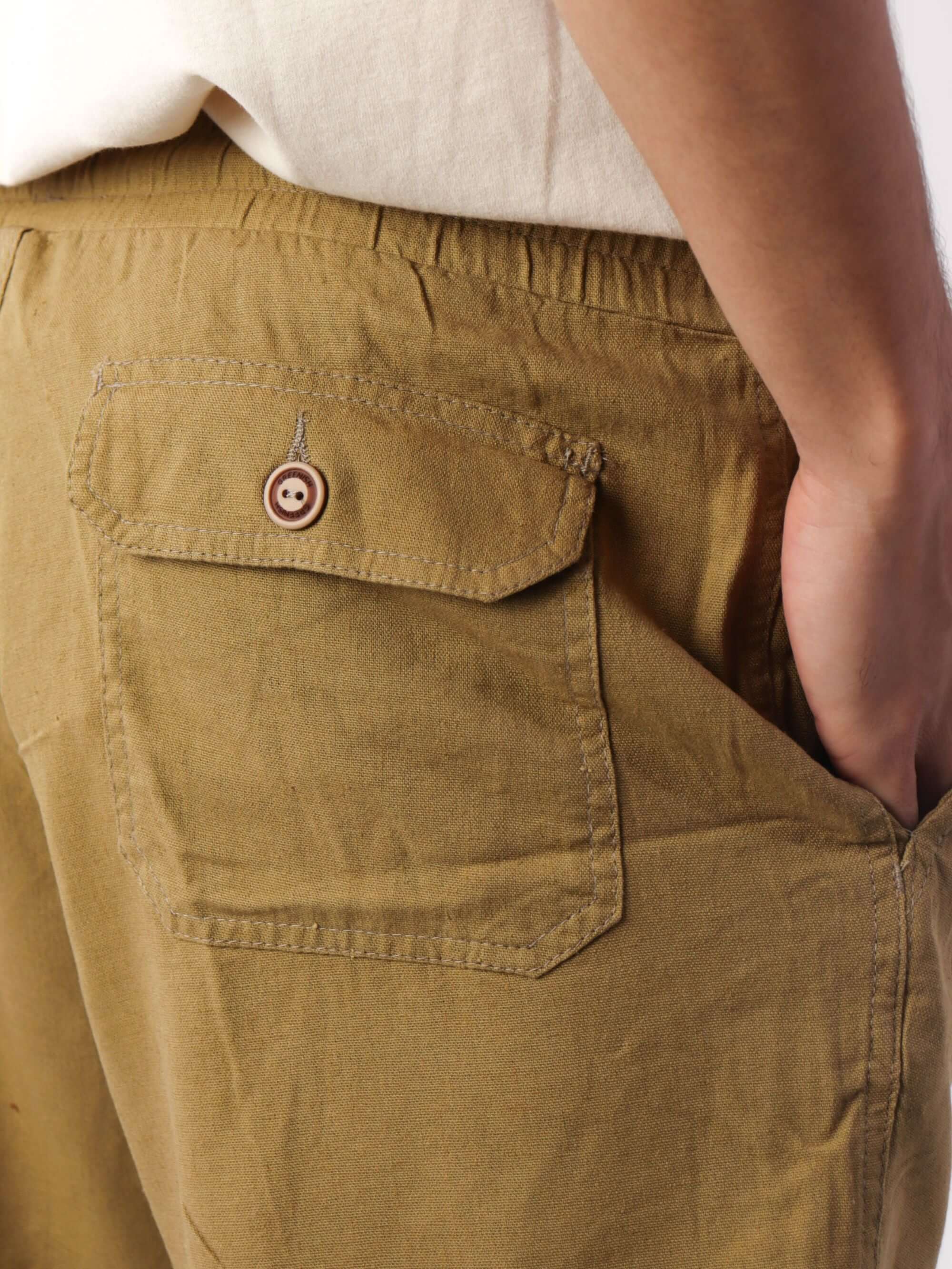 Detalhe do bolso traseiro do Short Linho Relax caqui da marca Greenish, com botão estiloso e acabamento confortável.