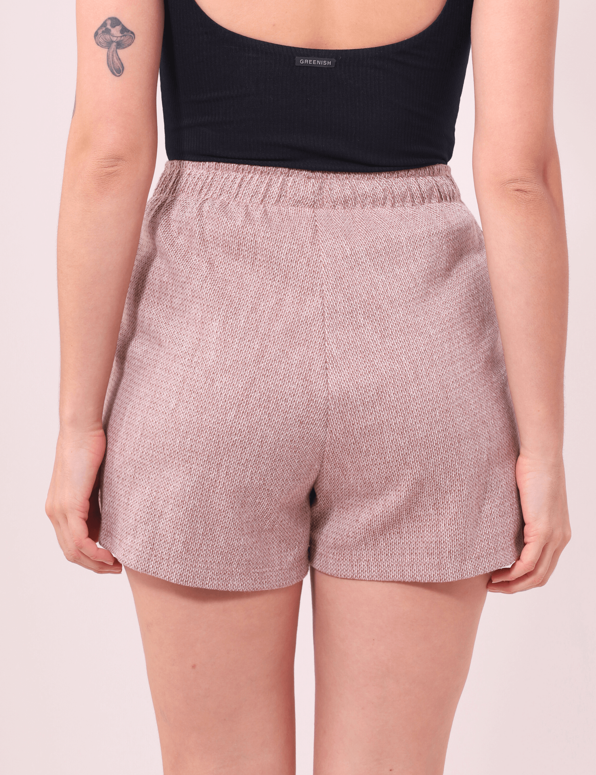 Mulher vestindo Short Salty Bege da Greenish, com cintura alta e textura rústica. Conforto e estilo em moletom leve. Vista traseira.