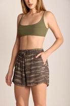 Woman wearing green crop top and brown patterned shorts, showcasing casual beachwear style and comfort.