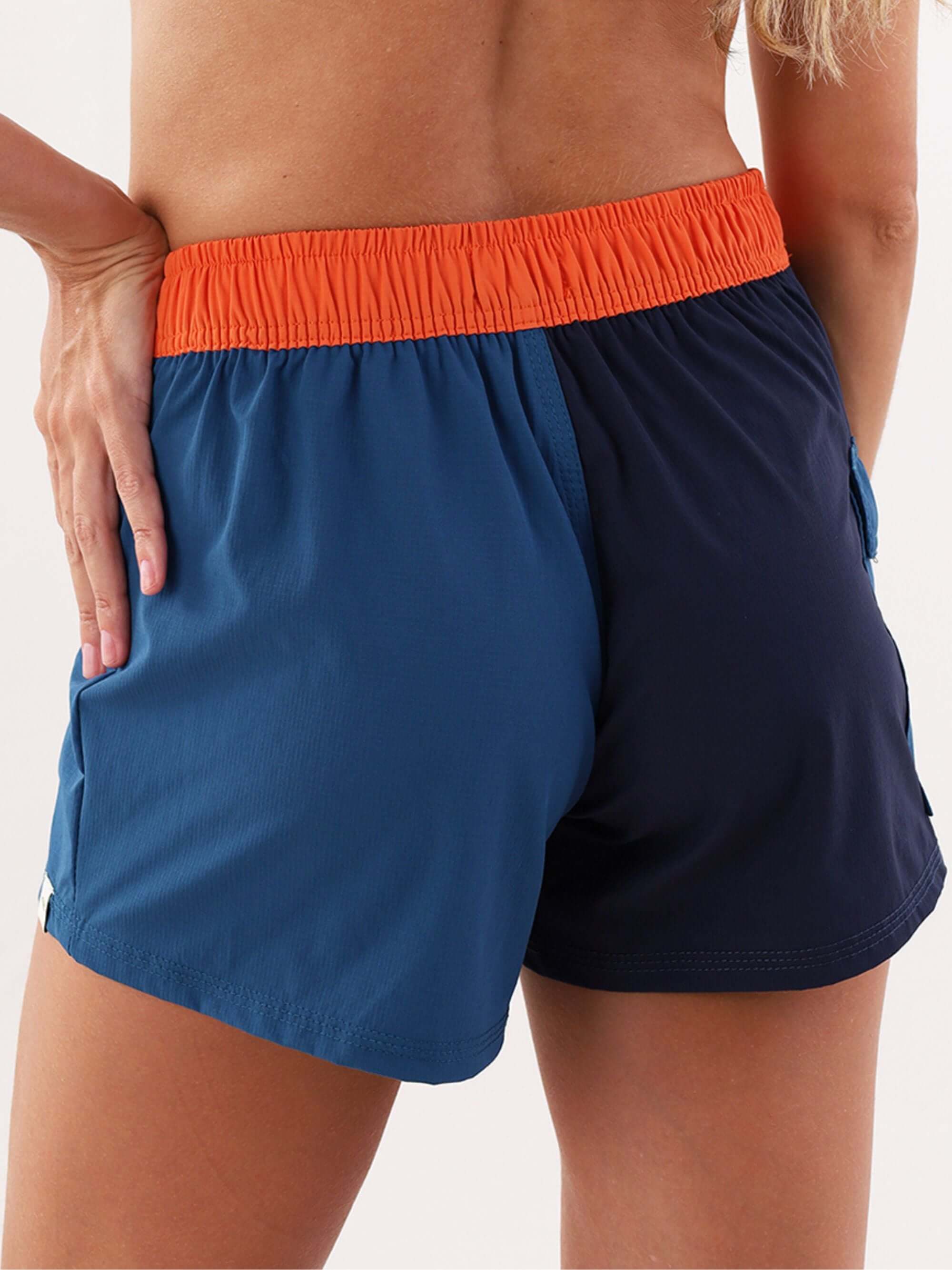 Short esportivo Talita da Greenish em azul marinho com detalhe laranja na cintura, ideal para atividades físicas.