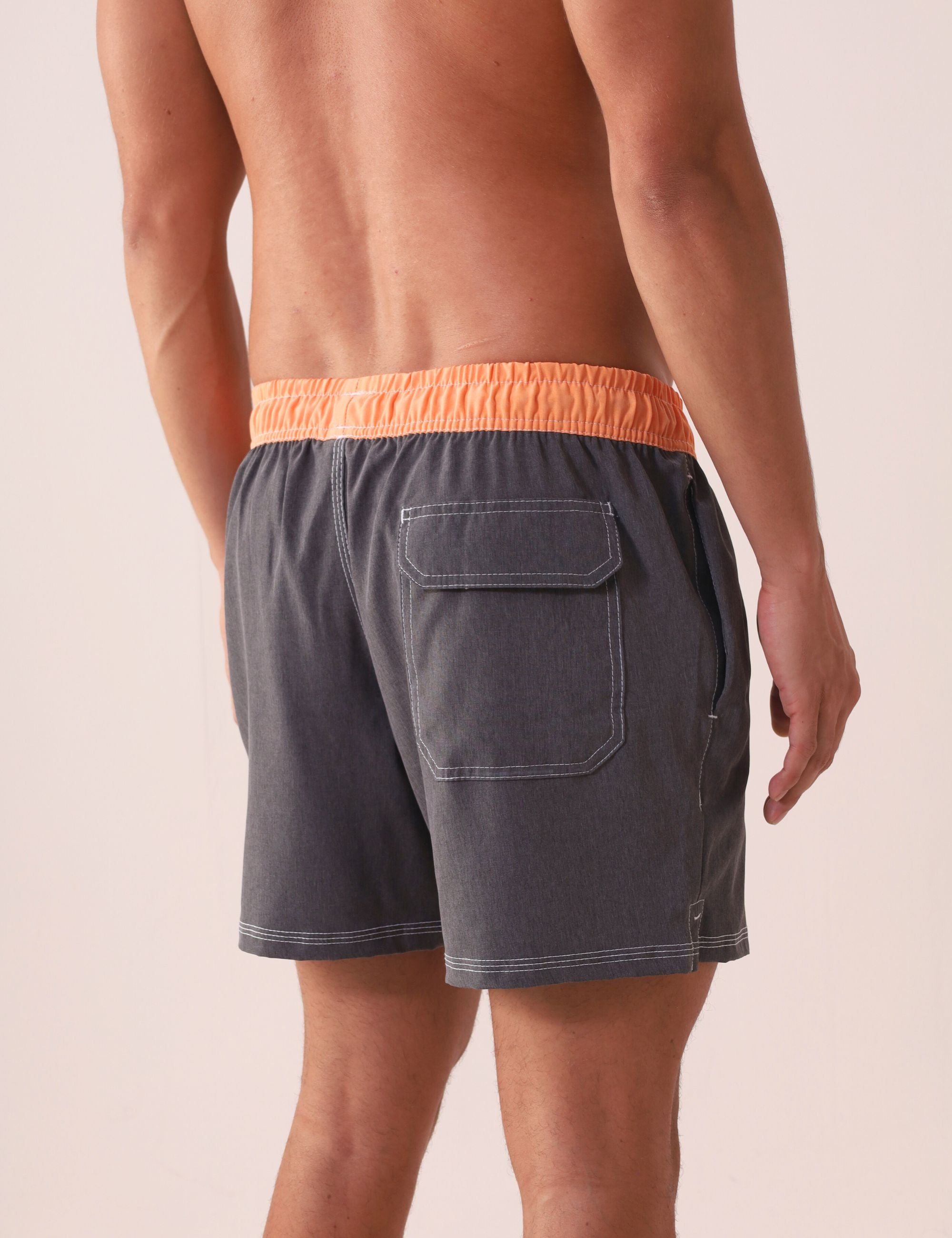 Modelo usando Short Vôley Blend - Grafite da Greenish com cós laranja, bolso traseiro e costura branca contrastante.