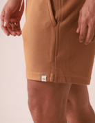 SHORT MOLETOM ARTISAN - AMARELO ESCURO da Greenish visto de lado, destacando bolso faca e textura da malha versa em amarelo escuro.