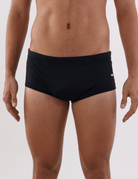 Homem vestindo sunga cavada preta da marca Greenish, ideal para atividades ao ar livre.