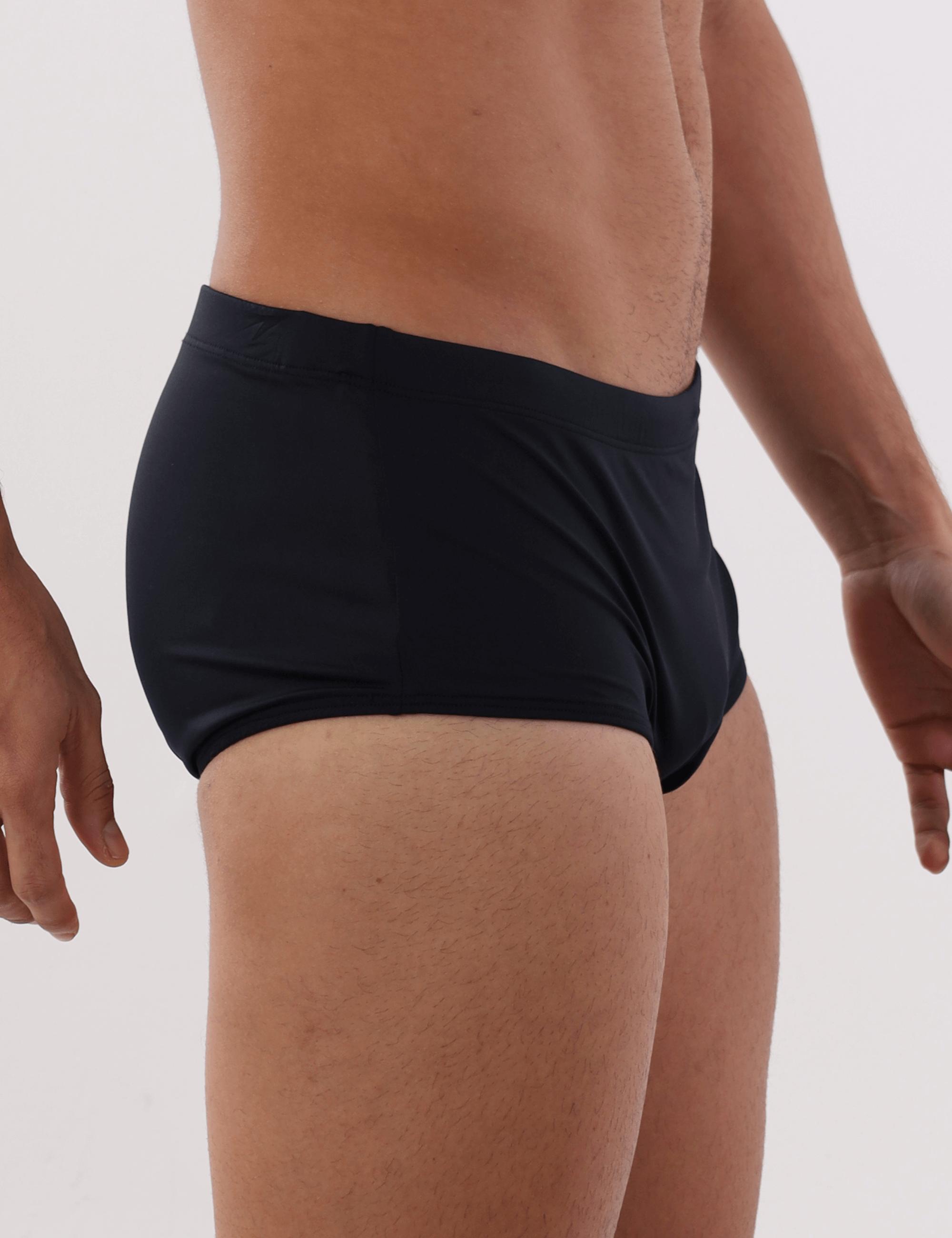 Homem usando sunga preta básica Greenish, vista lateral, ideal para atividades ao ar livre.