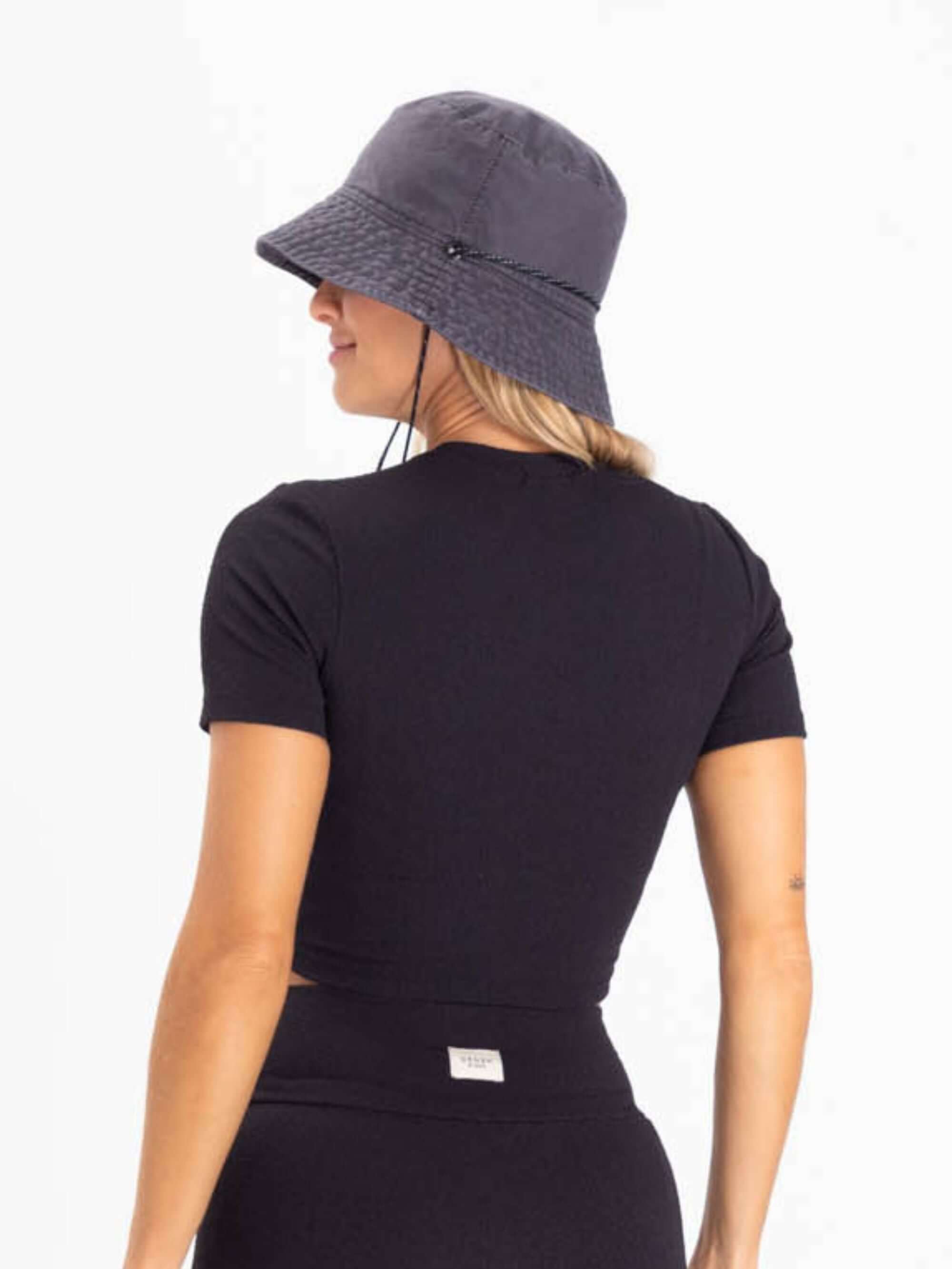 Modelo feminina usando blusa preta e chapéu, mostrando o estilo casual e moderno da Greenish.