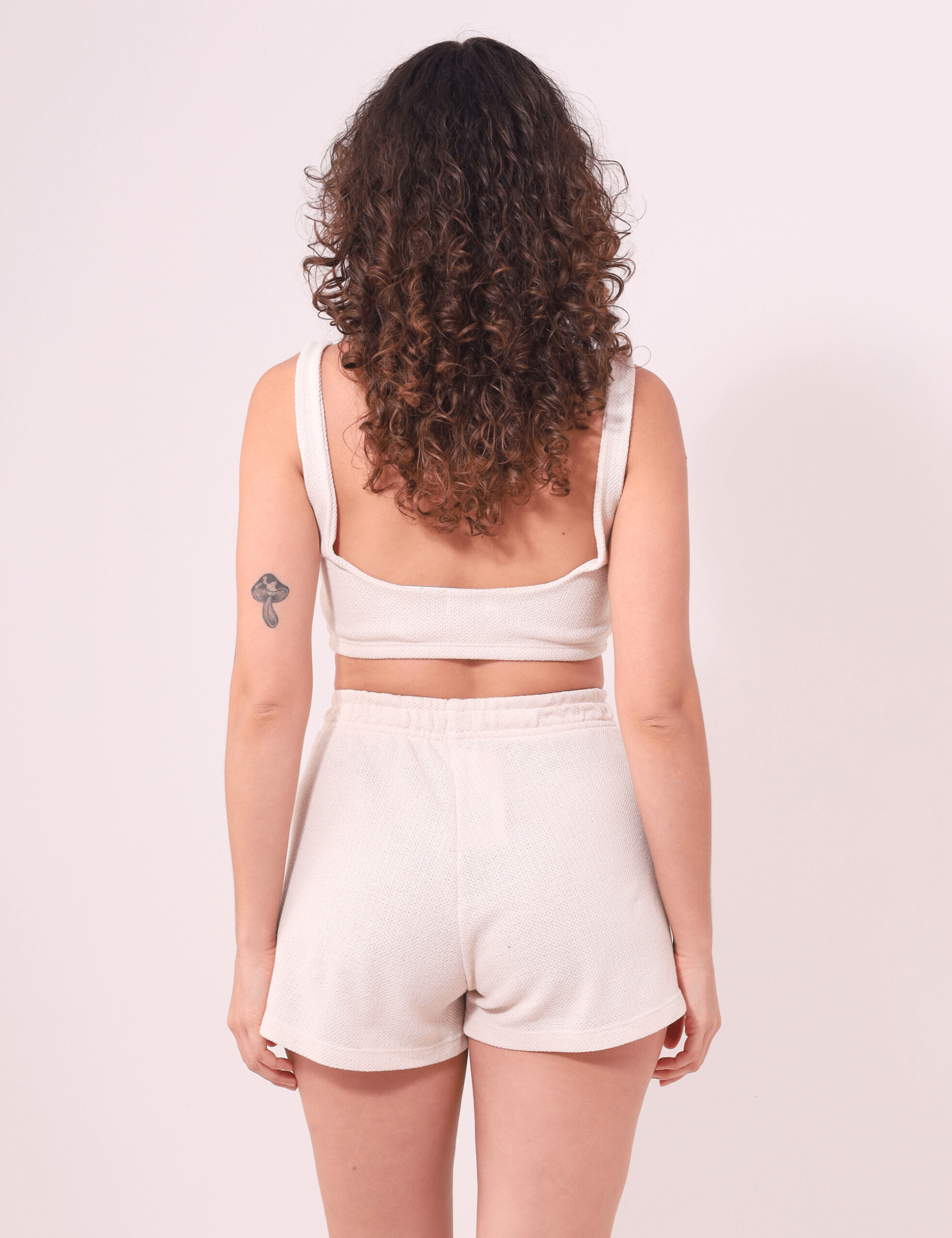 Mulher de costas vestindo Top Nalu Bege da Greenish, essencial para looks descontraídos com conforto e firmeza.