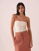 Modelo usando TOP RETO VALERIE - OFF WHITE da Greenish, sem alças, decote reto, feito de algodão sustentável, estilo minimalista.