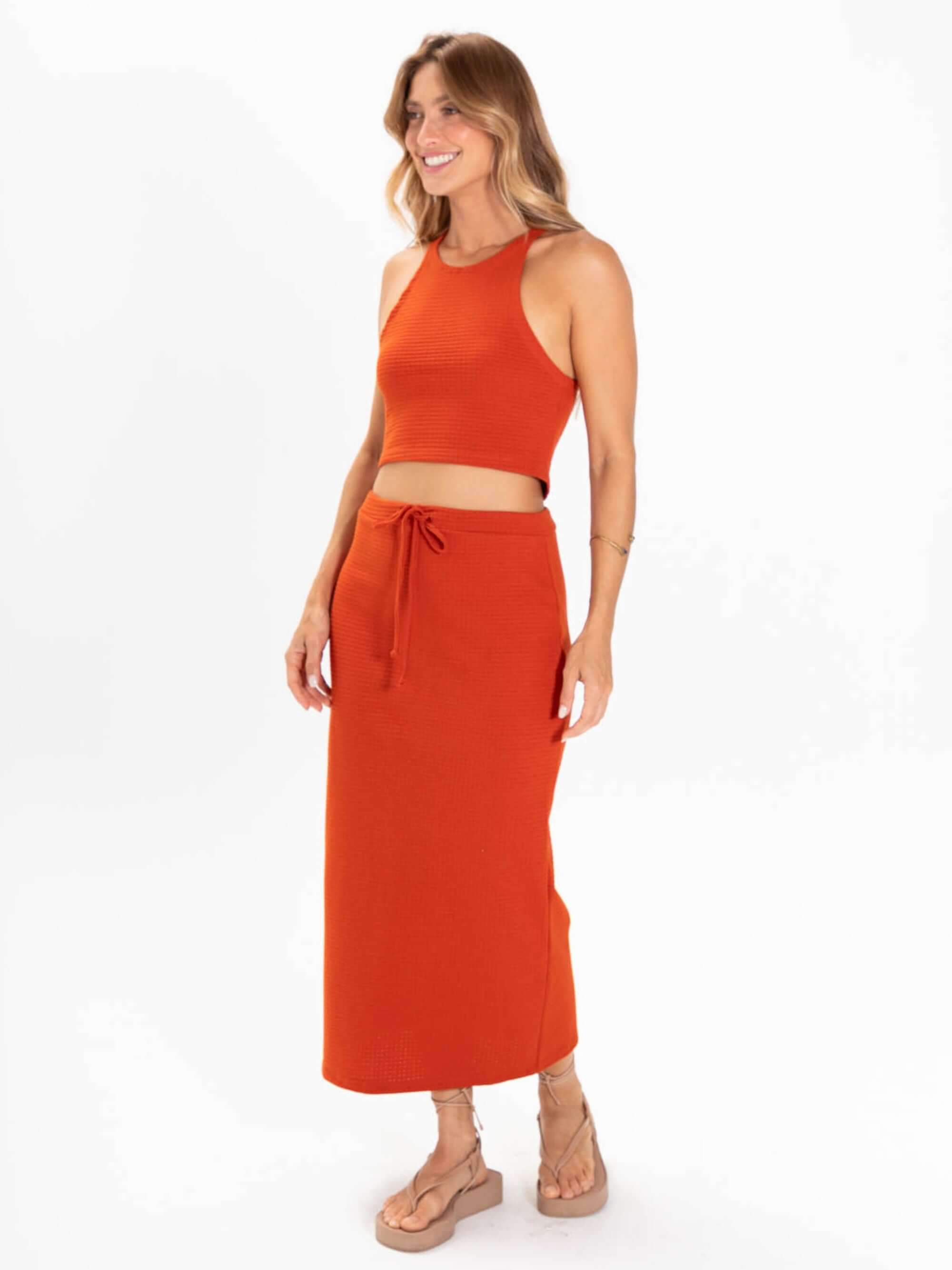 Top tricot Issy da Greenish em cor laranja, com cropped estilo regatinha e saia longa, perfeita para looks versáteis.