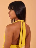 Modelo usando vestido curto Milla amarelo da Greenish, mostrando detalhes nas costas e fitagem do estilo.