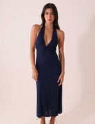 Mulher vestindo Vestido Longo Breeze - Azul Marinho com decote em V, em fundo claro.